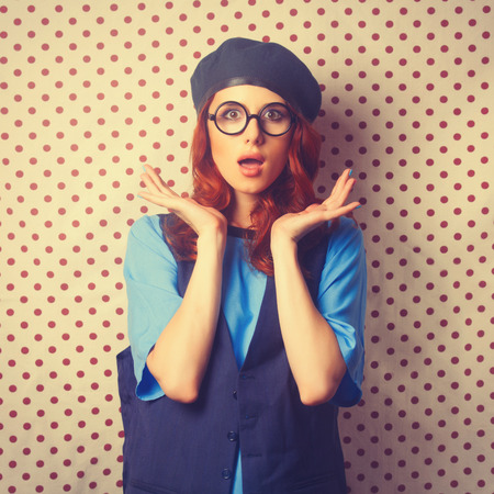 Surprised redhead girl in glasses on retro Polka dot background.の写真素材