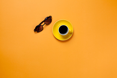 Cup of coffee with glasses on orange blackboardの写真素材