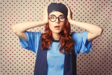 Surprised redhead girl in glasses on retro Polka dot background.の写真素材