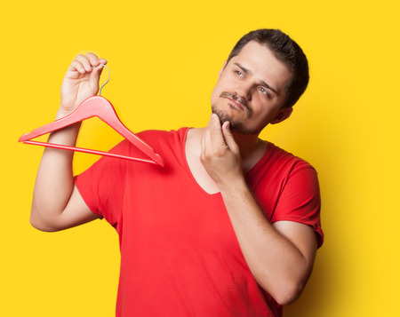 young guy in t-shirt with hanger on yellow background.の写真素材