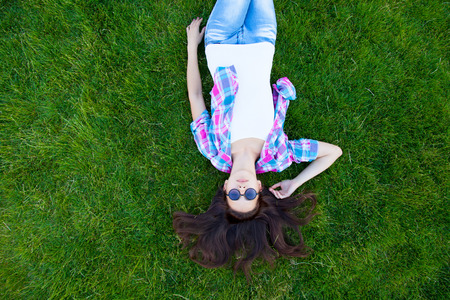 Young teen girl lying down on green grass in the park