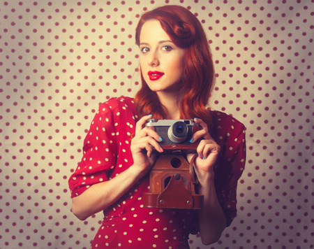 Portrait of redhead girl with retro camera on Polka dot background.の写真素材