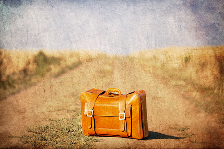 Old suitcase at country side road. Image in old color style.の写真素材