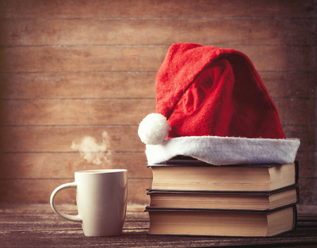 Santas hat over books near hot cup of coffee or tea  on wooden background.の写真素材