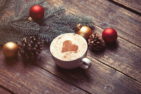 Cup of coffee and christmas toys on wooden table.