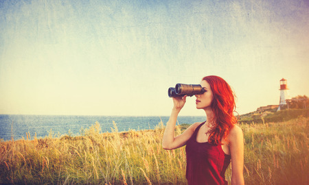young redhead girl with binocular near Lighthouseの写真素材