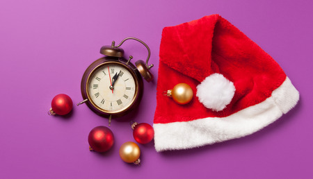 Alarm clock and Santas hat on violet background.の写真素材