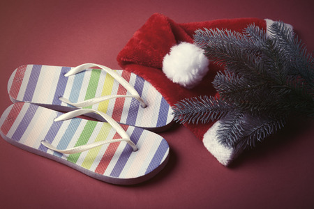 Flip flops and Santas hat on red background.の写真素材