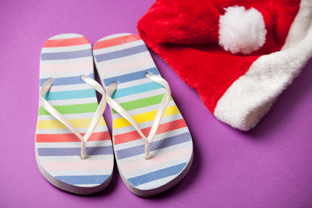 Santas hat and flip flops on violet background.の写真素材