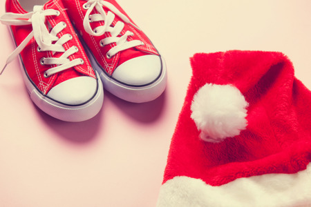 Santas hat and red gumshoes on pink background.