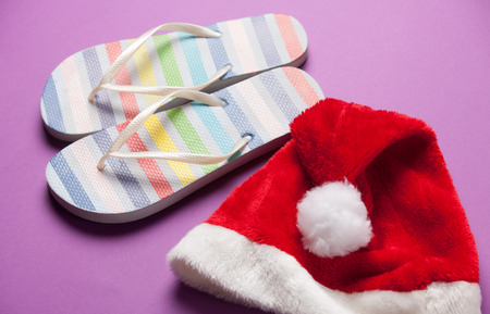 Santas hat and flip flops on violet background.の写真素材