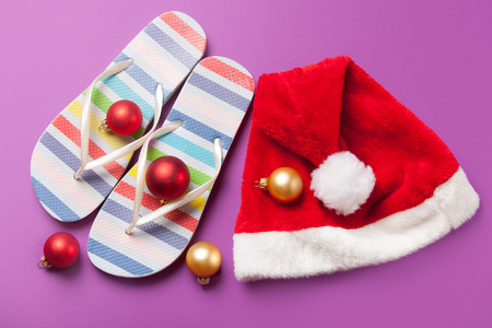Santas hat and flip flops with christmas bubbles on violet background.の写真素材