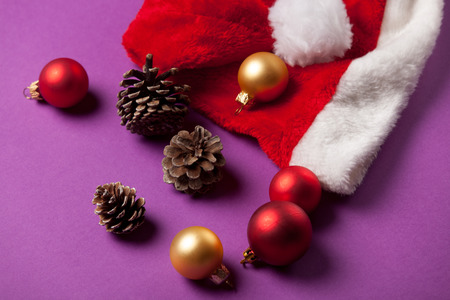 Pine cone and Santas hat on violet background.の写真素材