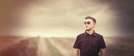 Young man in sunglasses at countryside outdoor. Photo in old color image style.の写真素材