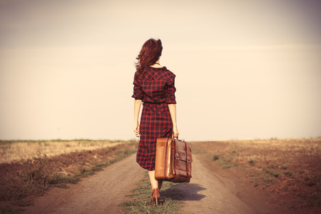 Beautiful girl in plaid dress with bag on countrysideの写真素材