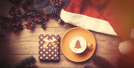 Cup of coffee and gift box with pine and hat on wooden table.の写真素材