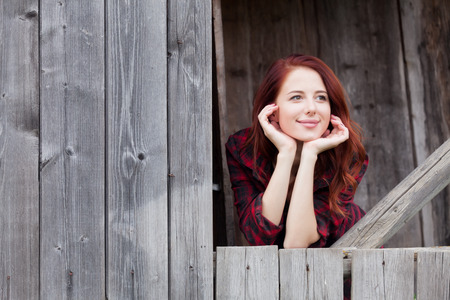Beautiful redhead girl near a wooden wall.の写真素材