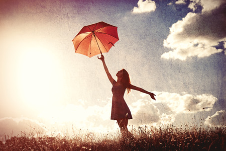 Silhouette of young women with umbrella on sky backgroundの写真素材