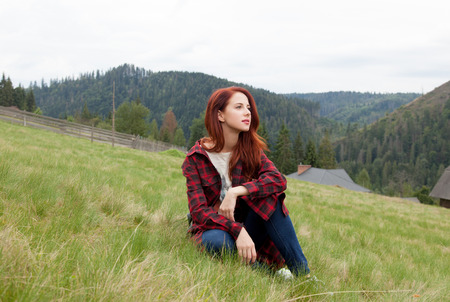 Portrait of a beautiful redhead women sitting on the grass in the forestの写真素材