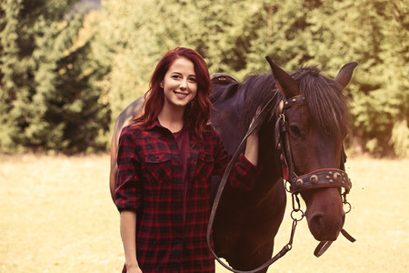 Redhead girl with horse in the forest