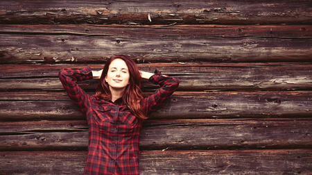 Portrait of a redhead woomen in tartan on wooden backgroundの写真素材