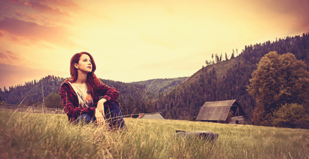 Portrait of a beautiful redhead women sitting on the grassの写真素材