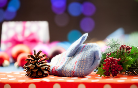 Mittens and gifts with Christmas lights on background.