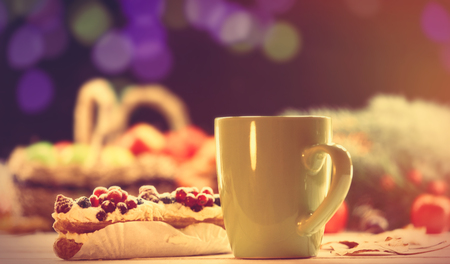 Eclair and cup of coffee on wooden table.