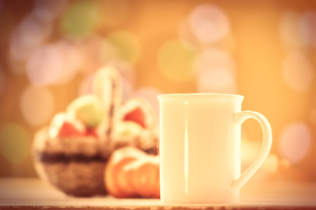 Pumpkin, basket with apples and cup of coffee or tea on yellow background.の写真素材