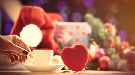Women putting down a cup near a heart shape toy on Christmas backgroundの写真素材