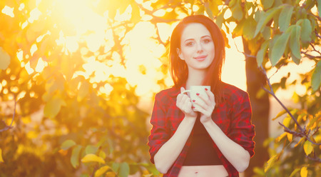 Woman with cup of tea or coffee at outdoor in autumn timeの写真素材