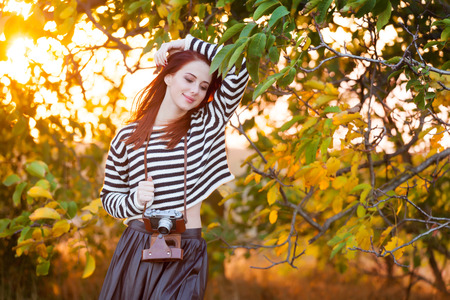 Woman with retro camera in autumn time outdoorの写真素材