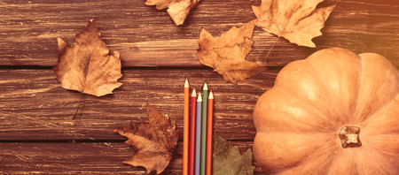 Pumpkin and pencils on wooden tableの写真素材