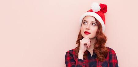 Redhead girl in Santa Claus hat on pink backgroundの写真素材