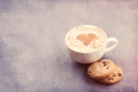 Cup of cappuccino with heart shape cacao and gingerbread on grey backgroundの写真素材