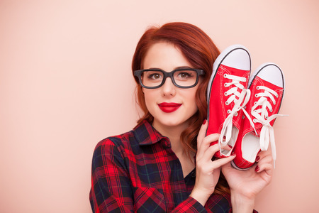 Redhead girl in glasses with red gumshoes on pink backgroundの写真素材
