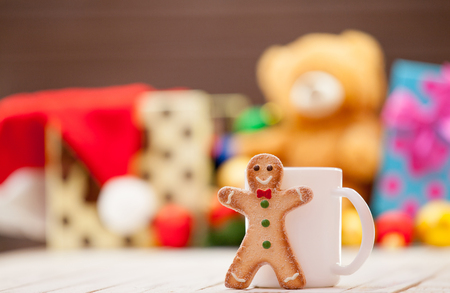 Cup of tea or coffee with gingerbread man and christmas gifts on backgroundの写真素材
