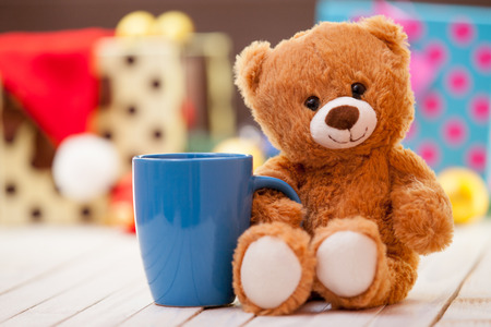 Teddy bear with cup of coffee or tea on christmas backgroundの写真素材