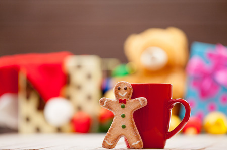 Cup of tea or coffee with gingerbread man and christmas gifts on backgroundの写真素材