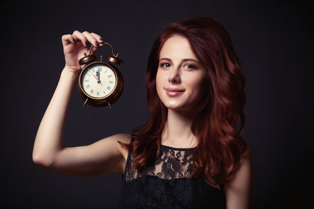 Portrait of a beautiful woman in style dress with retro alarm clock on dark backgorundの写真素材