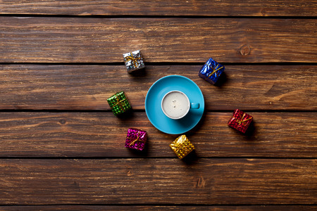 Gifts and cup of coffee on wooden backgroundの写真素材