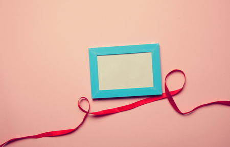 Photo frame and romantic ribbon on pink backgroundの写真素材