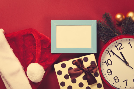 Huge clock and gifts with christmas tree branch on red background.