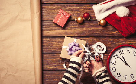 Female hands are wrapping a christmas gift on wooden backgroundの写真素材