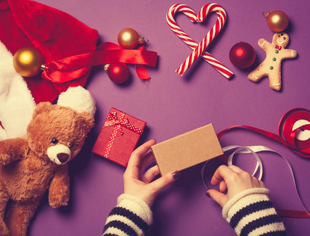 Female hands are wrapping a christmas gift on violet backgroundの写真素材