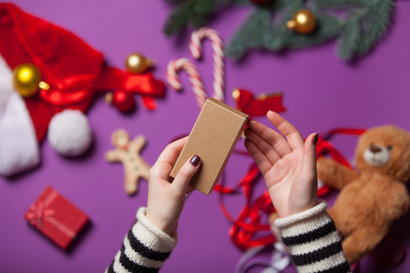 Female hands are wrapping a christmas gift on violet backgroundの写真素材