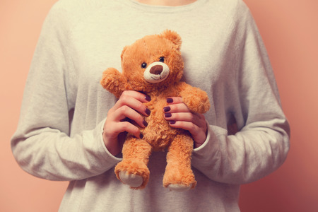 Woman holding teddy bear toy on pink backgroundの写真素材