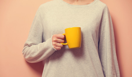 Young caucasian woman holding a yellow cupの写真素材