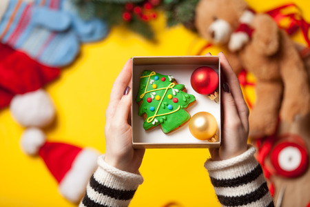 Woman wrapping gingerbread cookie as a Christmas gift. High point of view
