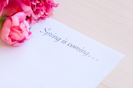 Paper with words Spring in coming and flower on the tableの写真素材